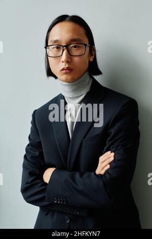Portrait vertical à la taille de l'homme d'affaires asiatique couronné de succès portant un costume et regardant l'appareil photo Banque D'Images