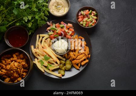 Shawarma avec sauce et légumes, avec poulet, frites et cornichons, cuisine traditionnelle arabe.Shawarma maison traditionnelle israélienne sur une assiette. Banque D'Images