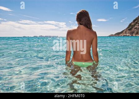 Jeune femme regardant l'horizon et debout dans l'eau cristalline en Sardaigne Banque D'Images