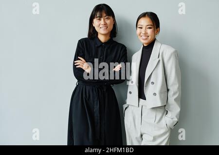 Portrait minimal de deux jeunes femmes d'affaires asiatiques souriant à l'appareil photo, espace de copie Banque D'Images