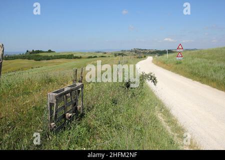 Les routes de gravier poussiéreuses typiques en Toscane en Italie avec une belle nature et un paysage autour et de vieilles maisons autour. Banque D'Images