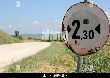 Les routes de gravier poussiéreuses typiques en Toscane en Italie avec une belle nature autour. Détail de l'affiche indiquant la largeur maximale autorisée des véhicules. Banque D'Images