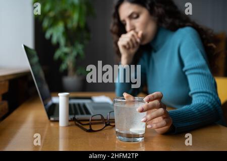 Une femme malade tousse et souffre de la grippe, prenant des médicaments antipyrétiques sur le lieu de travail Banque D'Images