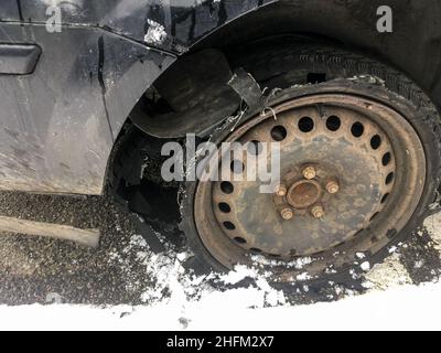 Détail de la roue rouillée avec pneu crevé et détruit sur le véhicule abandonné.Le pneu est complètement cassé avec la bande de roulement séparée. Banque D'Images