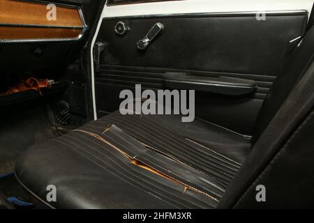 L'intérieur en cuir artificiel noir de l'ancienne voiture classique qui a besoin d'une rénovation.Avec des housses de siège déchirées détruites. Banque D'Images