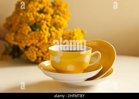 tasse jaune avec thé noir. thé rétro avec fleurs. tasse et assiettes vintage sur la table Banque D'Images