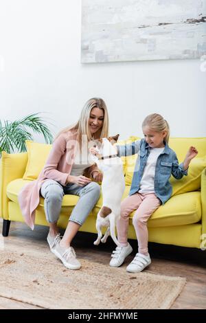Jack russell terrier sautant près d'une fille et d'une femme à la maison Banque D'Images