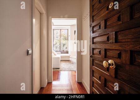 Entrée à un appartement de location avec de grandes fenêtres et une porte lambrissée en bois sombre Banque D'Images