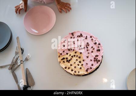 Vue de dessus d'un gâteau vegan maison avec glaçage rose placé sur la table à manger prêt à être servi. Banque D'Images