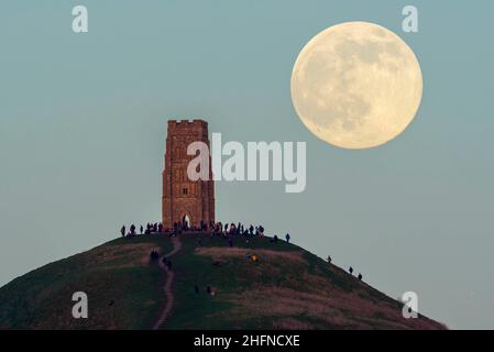 Glastonbury, Somerset, Royaume-Uni.17th janvier 2022.Météo Royaume-Uni.La pleine Lune du Loup s'élève derrière la Tour St Michael's sur Glastonbury Tor dans le Somerset lors d'une soirée froide et claire alors que les gens se tiennent au sommet et la regardent monter.Crédit photo : Graham Hunt/Alamy Live News Banque D'Images