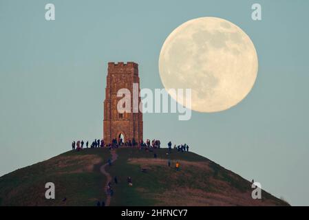 Glastonbury, Somerset, Royaume-Uni.17th janvier 2022.Météo Royaume-Uni.La pleine Lune du Loup s'élève derrière la Tour St Michael's sur Glastonbury Tor dans le Somerset lors d'une soirée froide et claire alors que les gens se tiennent au sommet et la regardent monter.Crédit photo : Graham Hunt/Alamy Live News Banque D'Images