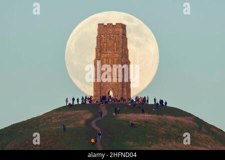 Glastonbury, Somerset, Royaume-Uni.17th janvier 2022.Météo Royaume-Uni.La pleine Lune du Loup s'élève derrière la Tour St Michael's sur Glastonbury Tor dans le Somerset lors d'une soirée froide et claire alors que les gens se tiennent au sommet et la regardent monter.Crédit photo : Graham Hunt/Alamy Live News Banque D'Images