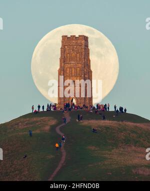 Glastonbury, Somerset, Royaume-Uni.17th janvier 2022.Météo Royaume-Uni.La pleine Lune du Loup s'élève derrière la Tour St Michael's sur Glastonbury Tor dans le Somerset lors d'une soirée froide et claire alors que les gens se tiennent au sommet et la regardent monter.Crédit photo : Graham Hunt/Alamy Live News Banque D'Images