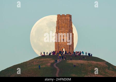 Glastonbury, Somerset, Royaume-Uni.17th janvier 2022.Météo Royaume-Uni.La pleine Lune du Loup s'élève derrière la Tour St Michael's sur Glastonbury Tor dans le Somerset lors d'une soirée froide et claire alors que les gens se tiennent au sommet et la regardent monter.Crédit photo : Graham Hunt/Alamy Live News Banque D'Images