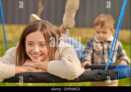 Jeune femme allongé sur balançoire et debout enfant Banque D'Images