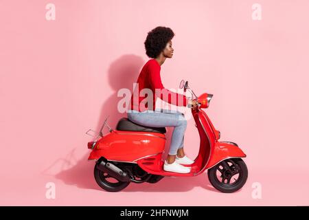 Pleine taille profil photo latérale afro-américaine jolie femme moto isolée sur fond rose pastel Banque D'Images