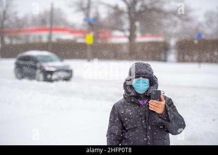 Un homme portant un masque facial avec son smartphone la neige abondante d' hiver dans une tempête d'hiver à Toronto, Canada Photo Stock - Alamy