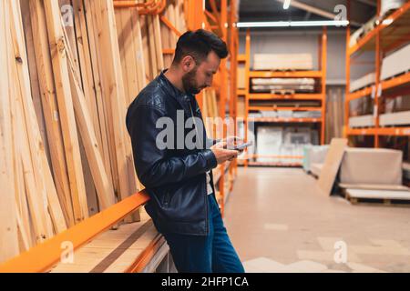 un acheteur dans un magasin de quincaillerie dans le département du bois choisit des planches et des barres de bois pour construire une maison. Banque D'Images