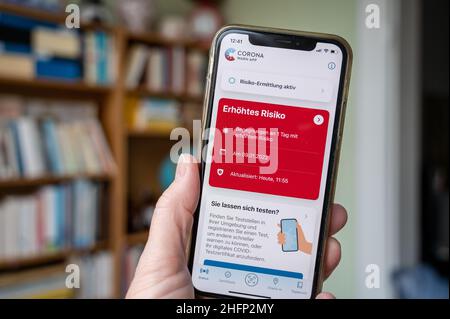 Eine Hand hält ein smartphone mit einer Infektionswarnung im Corona-App Display Banque D'Images