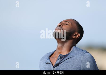 Homme détendu avec peau noire respirant de l'air frais dehors dans la montagne Banque D'Images