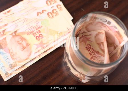 Quelque 50 liras turques à sauver dans un pot sur fond marron. Banque D'Images