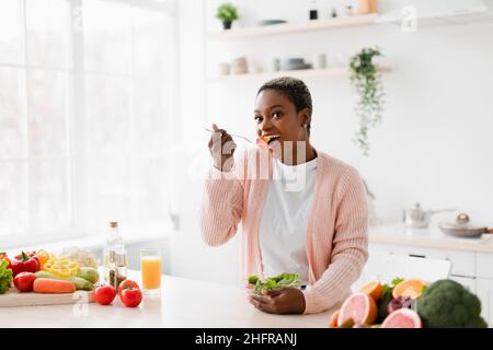 Joyeuse millénaires jolie salade noire de manger à la table avec des fruits et des légumes biologiques Banque D'Images