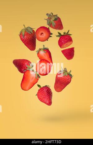 Composition créative avec des fraises mûres flottantes, leveuses et disloquées sur fond jaune.Vitamines, concept d'aliments frais et sains.Fruit minimal Banque D'Images