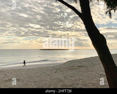 Femme marchant sur la plage de Kailua le matin sous un Cloudcover, Banque D'Images