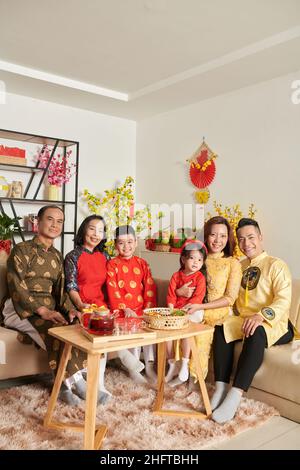 Grande famille rassemblée à la maison pour prendre du thé avec des bonbons et des fruits confits pour le nouvel an chinois Banque D'Images