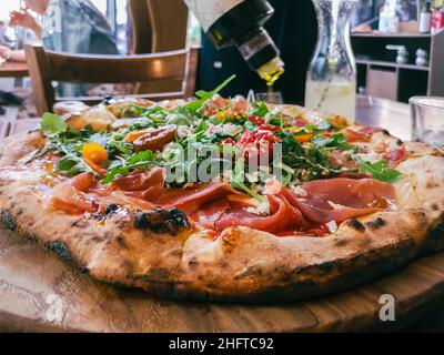 Vue rapprochée sur le versement d'huile d'olive sur une pizza dans un café Banque D'Images