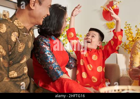 Un jeune garçon enthousiaste qui raconte un poème à ses grands-parents lors de la fête de Tet Banque D'Images