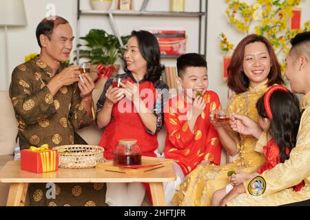 Une grande famille heureuse qui apprécie le thé avec des fruits confits et des bonbons lors de la fête de la mise à la maison Banque D'Images