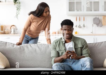 Une femme noire en colère regardant son petit ami bavarder avec des dames Banque D'Images