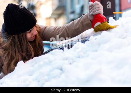 Une fille qui enlève la neige et la glace de la voiture Banque D'Images