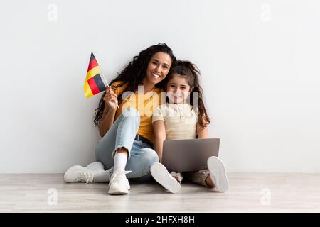 Bonne maman arabe et petite fille tenant ordinateur portable et drapeau de l'Allemagne Banque D'Images