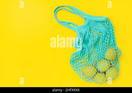 Citrons dans un sac réutilisable sur fond jaune. Vue de dessus, espace de copie Banque D'Images