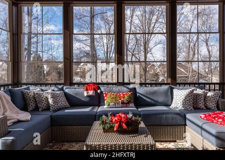 Confortable porche couvert en hiver pendant la saison des fêtes, toits enneigés et bois en arrière-plan. Banque D'Images