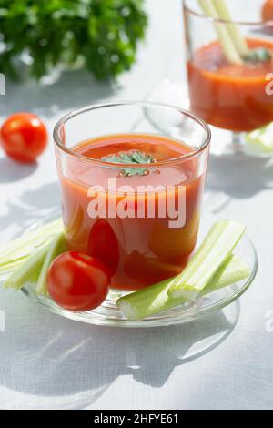 Deux verres avec jus de tomate frais, céleri, persil et tomates mûres Banque D'Images