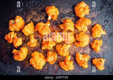 Marmites de chou-fleur de Buffalo fraîchement rôties sur une plaque de cuisson : fleurons de chou-fleur rôtis dans une sauce chaude sur une plaque de cuisson Banque D'Images