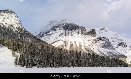 Parc national Yoho, Canada - décembre 23 2021 : le lac Emeraude gelé se cachant dans une forêt d'hiver surmontée par les montagnes rocheuses dans le parc national Yoho Banque D'Images