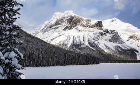 Parc national Yoho, Canada - décembre 23 2021 : le lac Emeraude gelé se cachant dans une forêt d'hiver surmontée par les montagnes rocheuses dans le parc national Yoho Banque D'Images