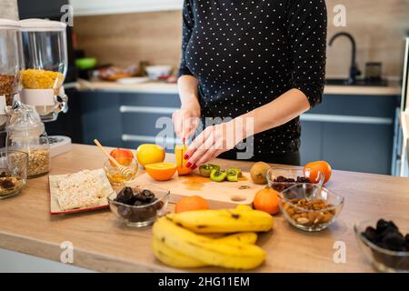 Gros plan sur la main de la femme caucasienne inconnue tenant le couteau coupant kiwi et oranges copier l'espace Banque D'Images