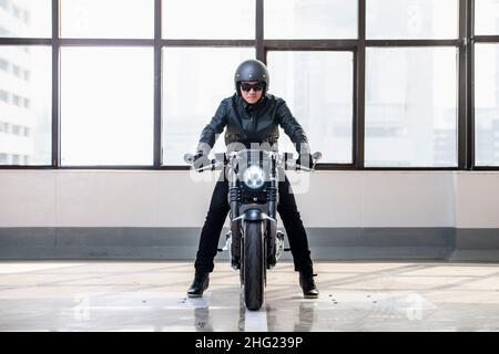 Homme sur sa moto électrique dans un bâtiment industriel de Bangkok Banque D'Images