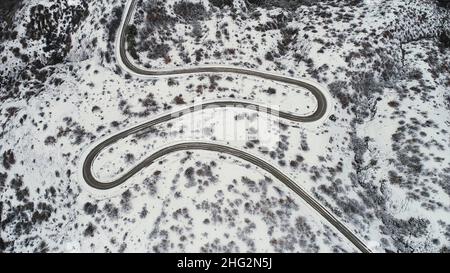 Vue aérienne de dessus de neige paysage de montagne avec des arbres, route et bleu mer rivage.Magnifique paysage de la route d'hiver dans les champs enneigés près de la côte. Banque D'Images