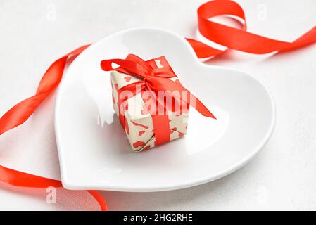 Magnifique assiette en forme de coeur et boîte cadeau sur fond blanc Banque D'Images