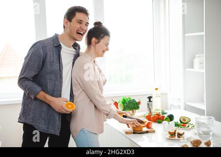 Homme parlant avec sa femme en train de cuisiner des aliments sains en appréciant la préparation d'un dîner romantique dans la cuisine.Couple préparant le dîner.Alimentation saine, alimentation.Cuisson Banque D'Images