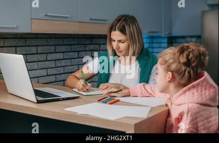 Une mère caucasienne aide la fille scolaire à préparer ses devoirs.Éducation des enfants.Soins familiaux. Banque D'Images