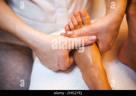 Portrait en gros plan d'un massage sain du pied dans le salon de spa.Jeune femme soins de la peau.Fermez les mains. Banque D'Images