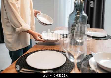 Jeune femme dans une chemise blanche mettant des assiettes sur la table Banque D'Images