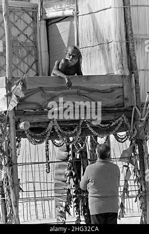 Indian Siddha Yogi saint Devraha Baba, se trouve sur son machan, une plate-forme de bois et de chaume, alors qu'il reçoit des dévotés sur les rives de la rivière Yamuna le 2 février 1989 près de Vrindavan, en Inde. Banque D'Images